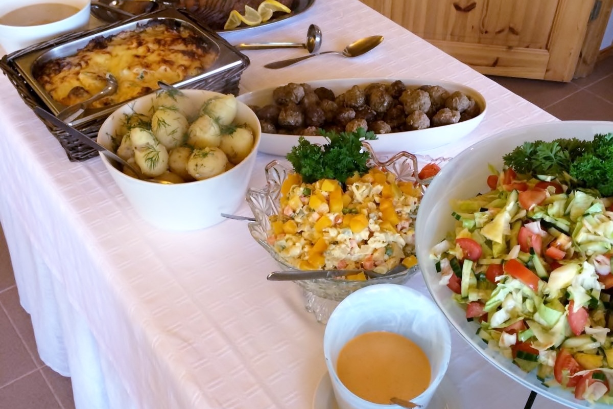 Juhlien tarjoilupöytä, jossa erilaisia ruokakulhoja täynnä ruokaa ja salaattia