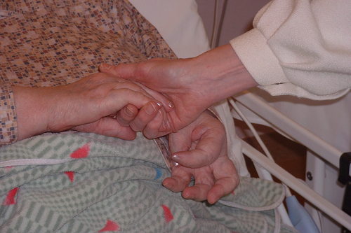 Sairaalapappi pitää potilaan kädestä kiinni